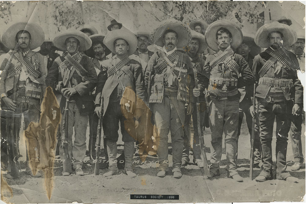 Clients bring the most interesting and valuable photos to Hawkins Studio for repair. This 1911 photo of Pancho Villa and His Gang was badly faded, cracked, and severely water damaged. It had been mistreated - including a stint served on the wall of a Baylor University dorm room in the 1960s. Back then a tongue-in-cheek plastic label had been affixed bearing the nickname of the gang of roommates in the dorm. Not surprisingly major portions of the picture were no longer decipherable. At high resolution Carol searched out and repainted many of these lost areas. Going area by area she corrected inappropriate color and contrast and added definition to faded facial features to increase recognizability of Pancho's gang. 